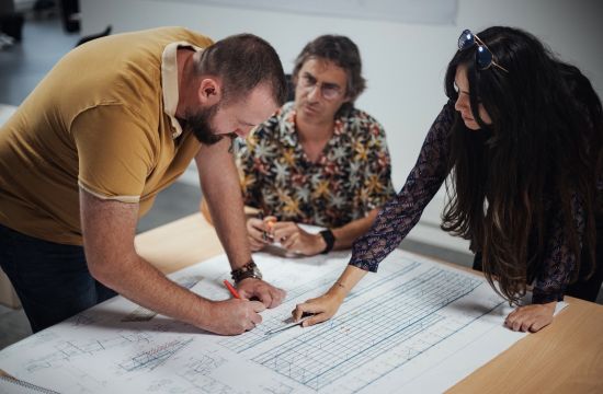 Collaborateurs du Bureau d'étude du groupe Le triangle en train d'échanger sur un dessin industriel pour une structure solaire